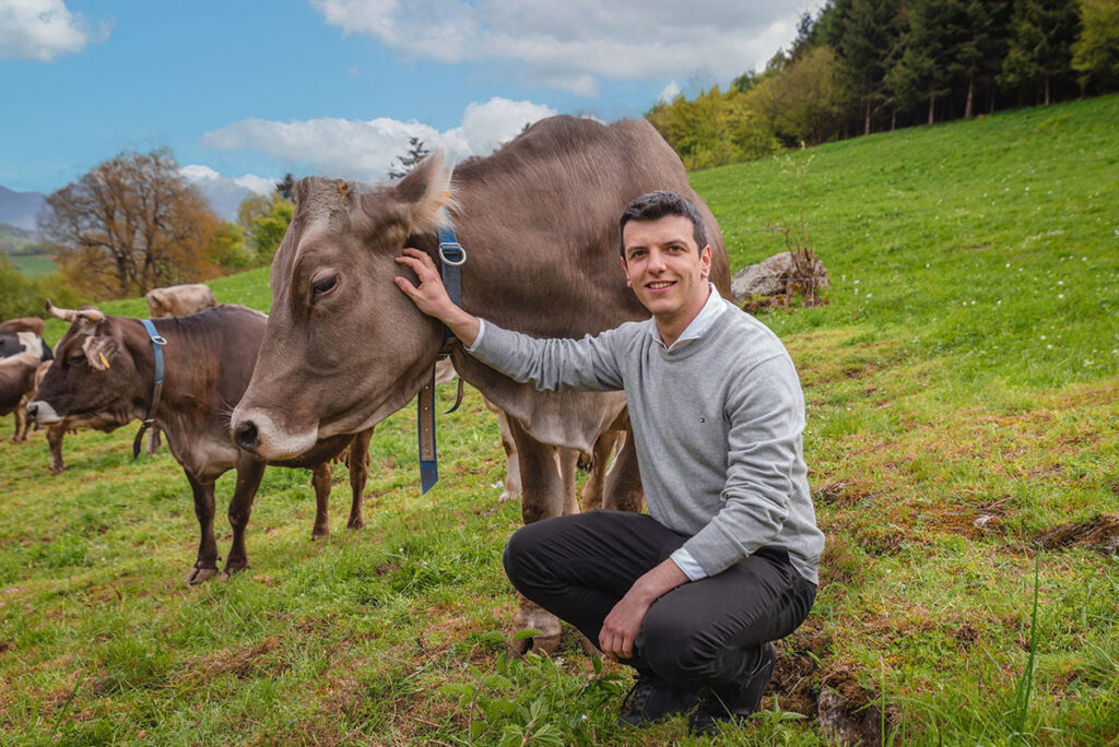 Mattia, fondateur de bbuono.it à côté d'une vache pour l'adoption à distance